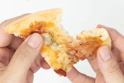 Two hands break apart a slice of pizza with cheese, meat, onions, and green bell peppers on top baked using a toaster oven.