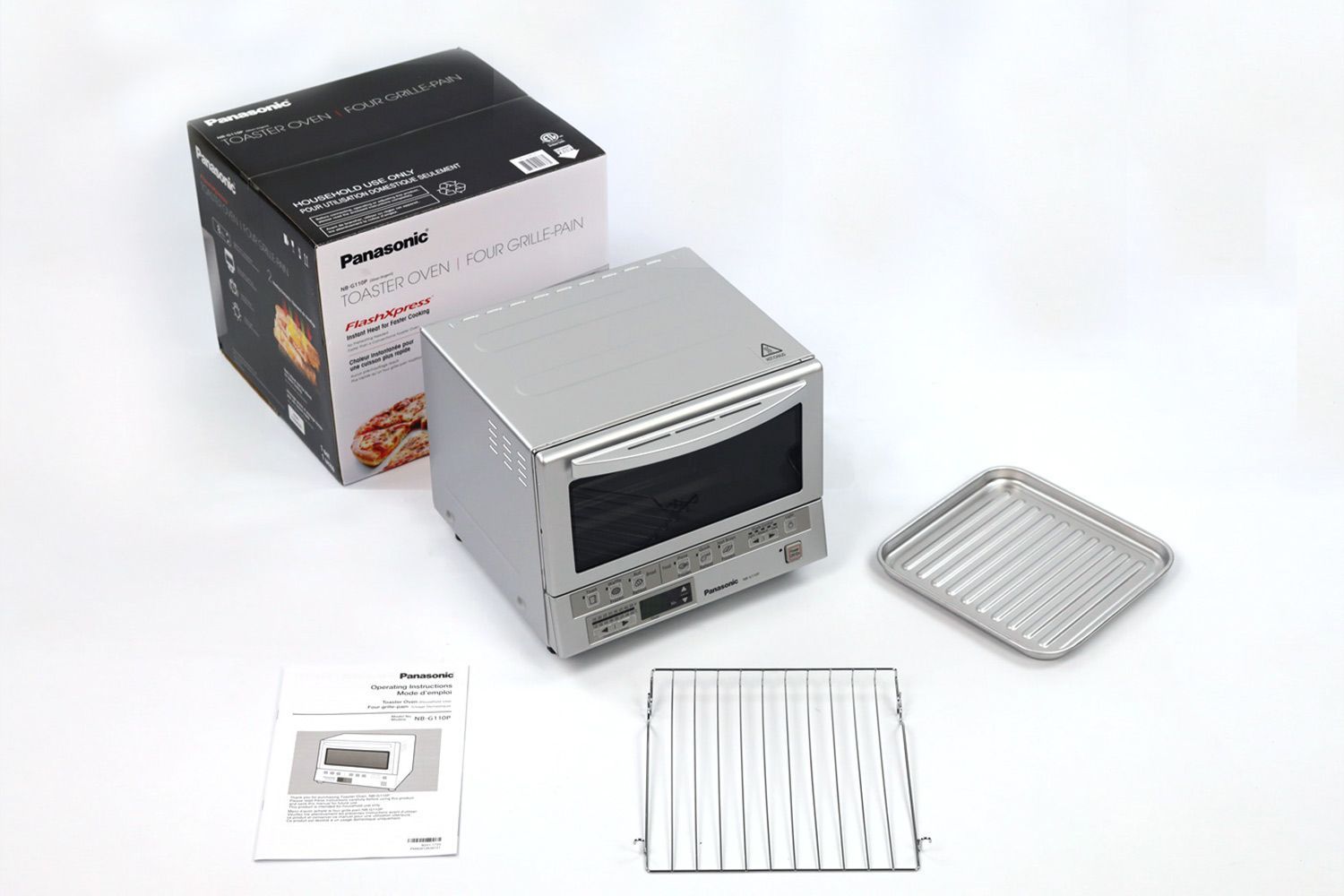 A box, the silver Panasonic NB-G110P FlashXpress Compact Toaster Oven, a user manual, an oven rack, and a baking pan.