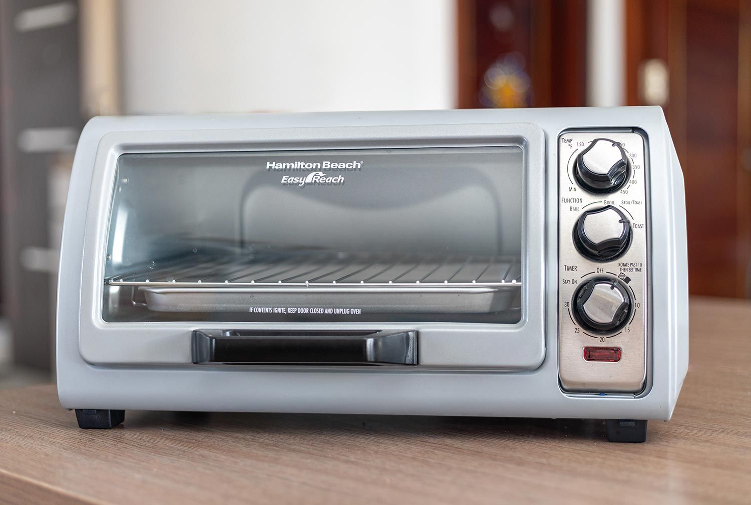 The front of a closed silver Hamilton Beach 31344DA 4-Slice Easy Reach with Roll Top Door Toaster Oven on a white background.