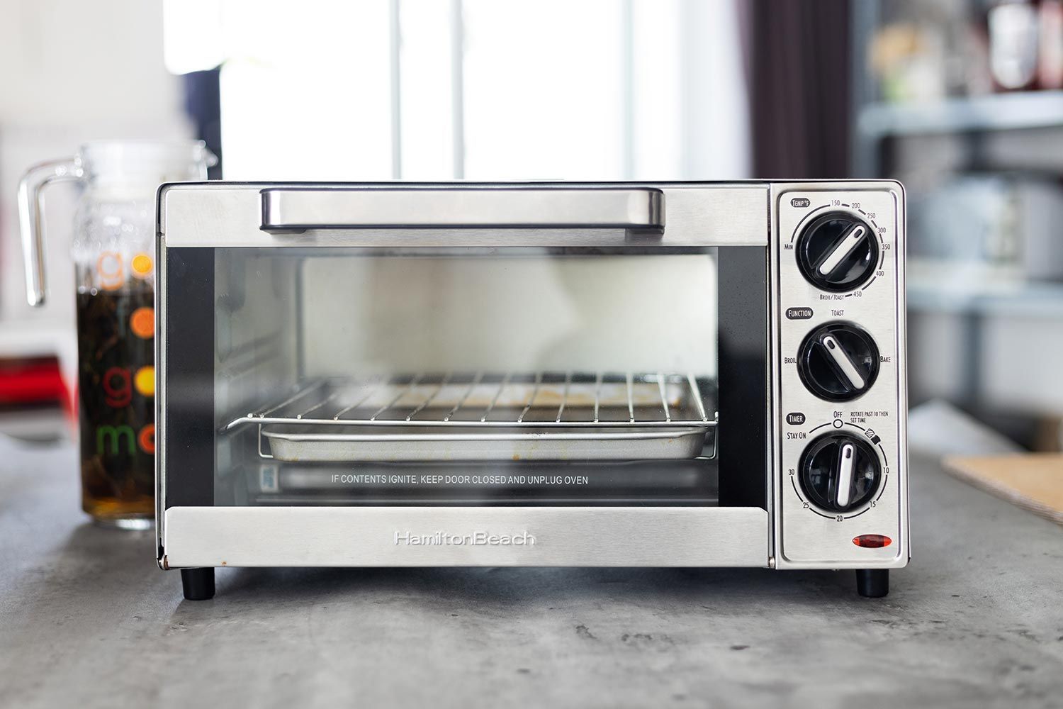 The front of a closed stainless steel Hamilton Beach 31401 4-Slice Capacity Countertop Toaster Oven on a white background.