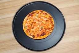 The full view of a baked 9-inch thick-crust meat pizza on an enamel pizza pan.