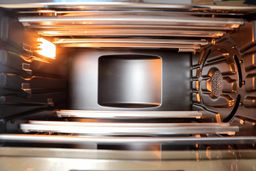 The cooking chamber of the Breville BOV900BSS Smart Oven Air Fryer Pro has an enamel non-stick coating, 4 guide rails with safety hooks, 4 top and 2 bottom quartz heating elements, a convection fan, and a light.