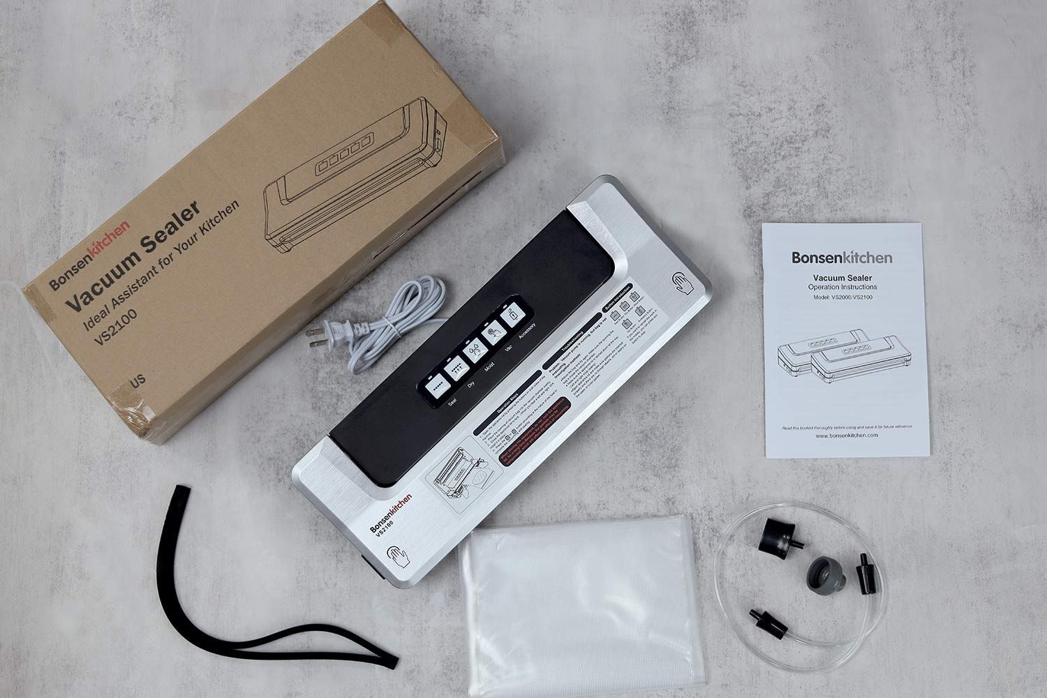 The content of the BonsenKitchen VS2100’s shipping box. You get a replaceable foam seal for the sealer, air hose and adapter, sheets of pre-cut plastic bags, and documentation.