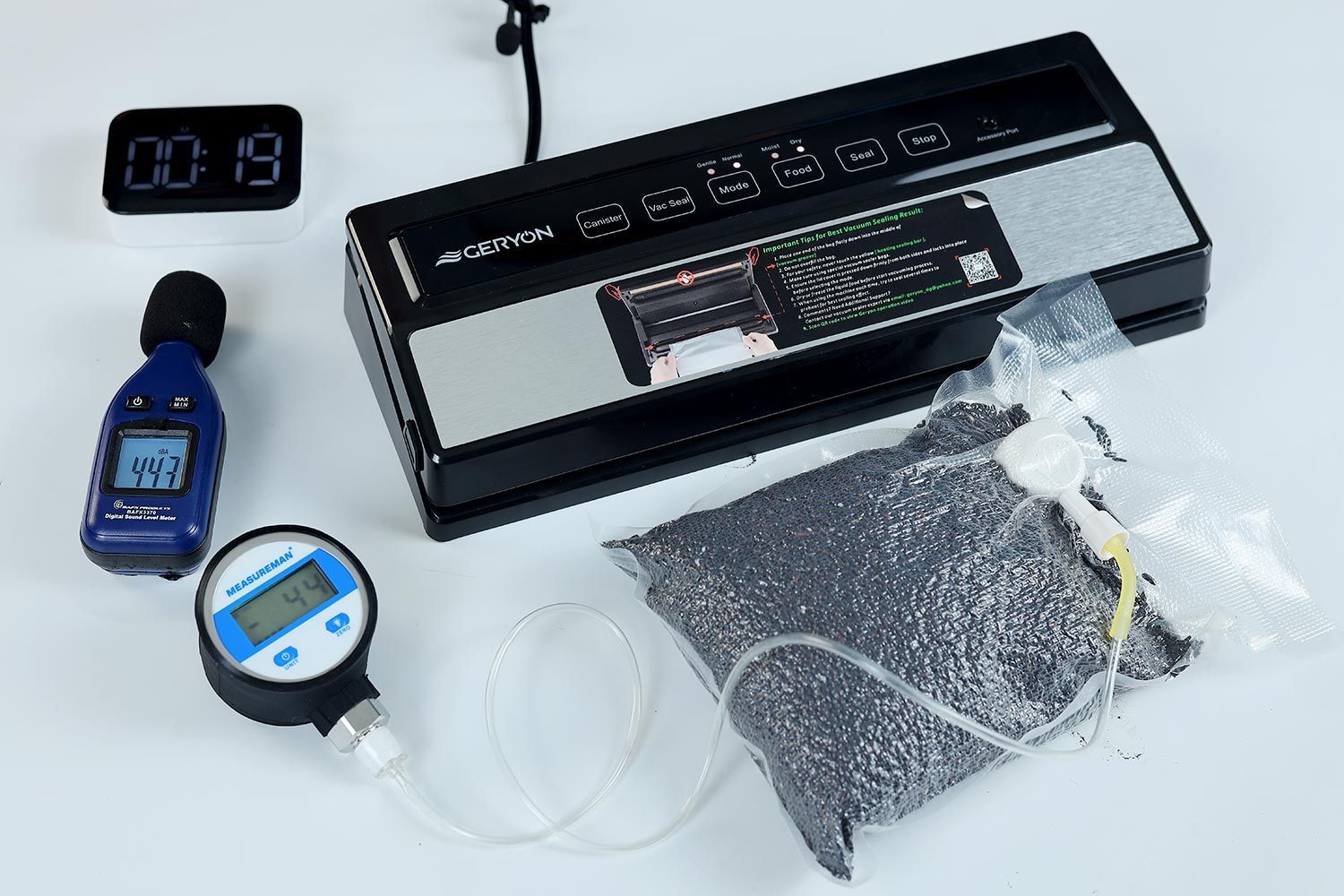 The Geryon E2900-MS vacuum sealer vacuum-packaging a bag of black rice grains. To the left is a vacuum pressure gauge reading 44 kPA.