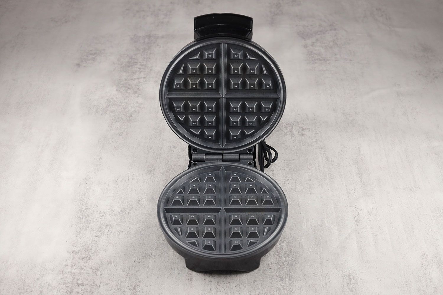 An overview of the waffle plates of the Oster waffle maker. It’s made from cast aluminum and has Belgian-style patterning.