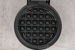 A close-up shot of the DASH Mini waffle maker’s waffle plate. It is black and treated with a layer of textured non-stick.