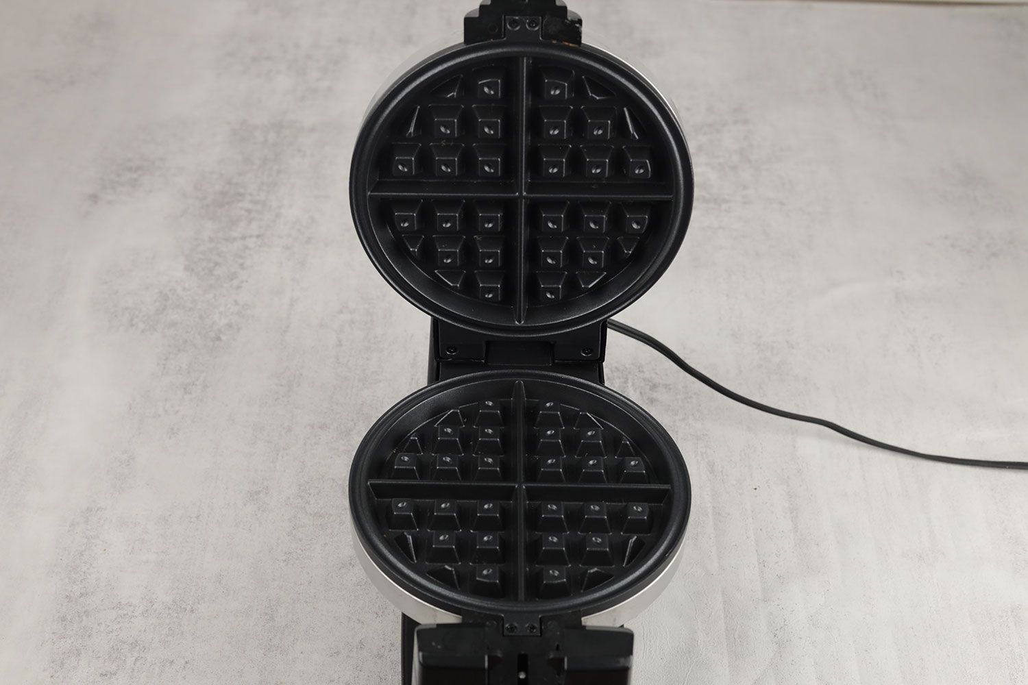 A close-up of one of the Bella 13991’s waffle plates. The plate has a Belgian-style patterning and a black non-stick coating.