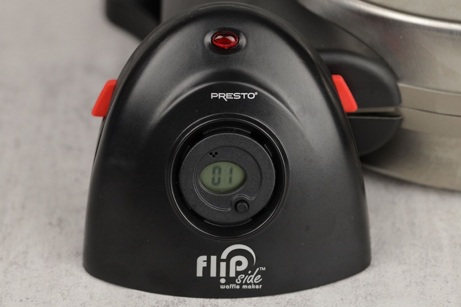 A close-up shot of the timer to the side of the Presto waffle maker’s base. A button and speaker holes are visible.