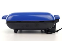 Side view of the DASH No Drip waffle maker. The blue top lid and the black bottom of the waffle maker can be seen here.