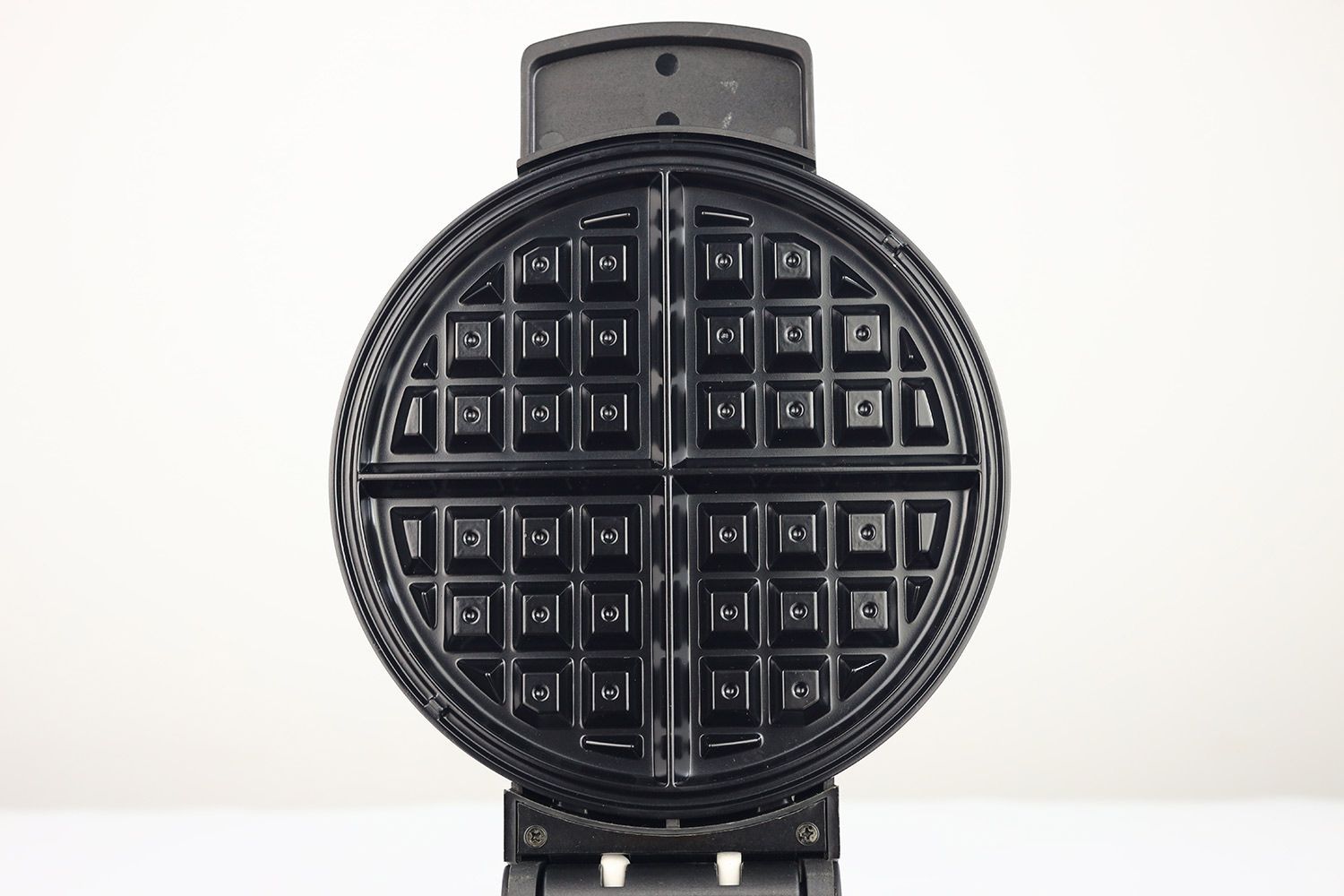 A close-up view of the glossy, black, Belgian-style waffle plate of the Black and Decker WMB500 waffle maker.