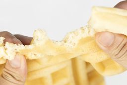 A waffle being torn up by hands to test for its consistency. This one was baked for 7 minutes using our Birch Benders batter.