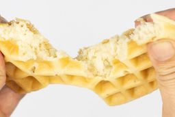 A waffle baked for 7 minutes using our Birch Benders waffle mix is torn down the middle by hands to test its consistency.