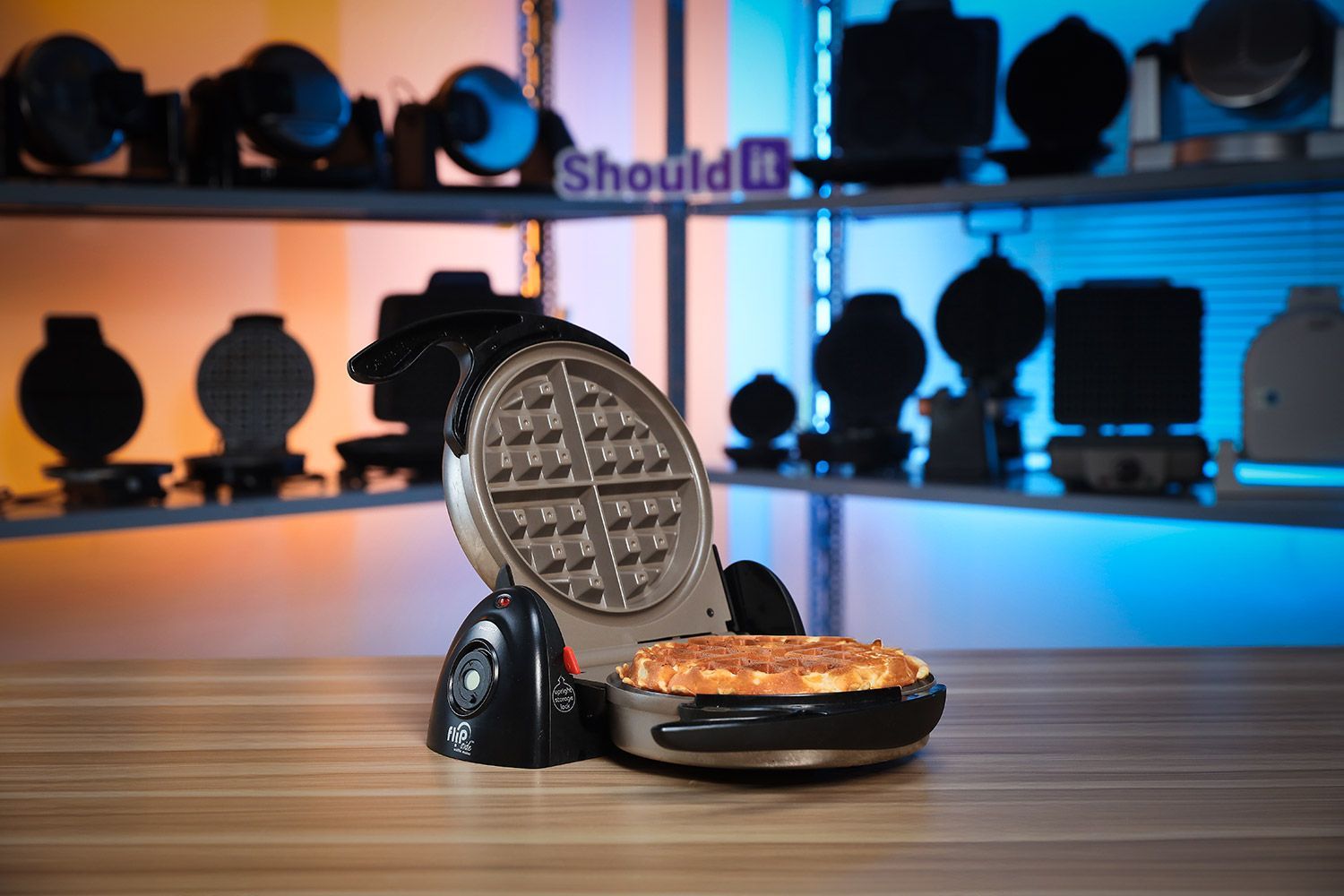 Presto Flipside waffle maker standing upright on a white countertop beside a plate of freshly-baked waffles.