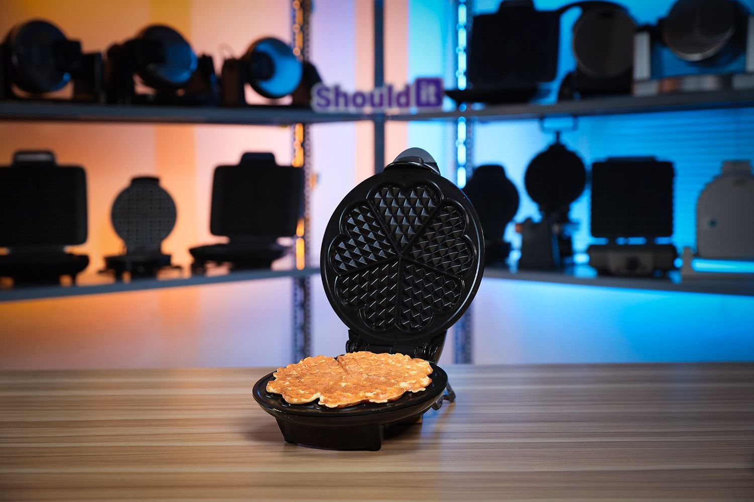 Euro Cuisine Heart-Shaped waffle maker with opened lid revealing its unique heart-shaped plates on a white countertop next to a plate of fresh waffles.