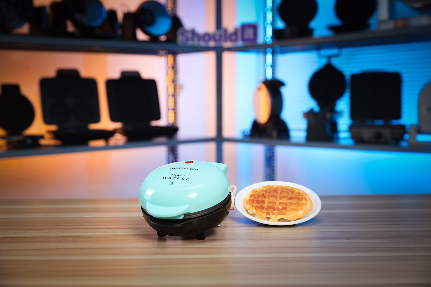 The Nostalgia MWF5AQ mini waffle maker next to its instruction manual and shipping box.