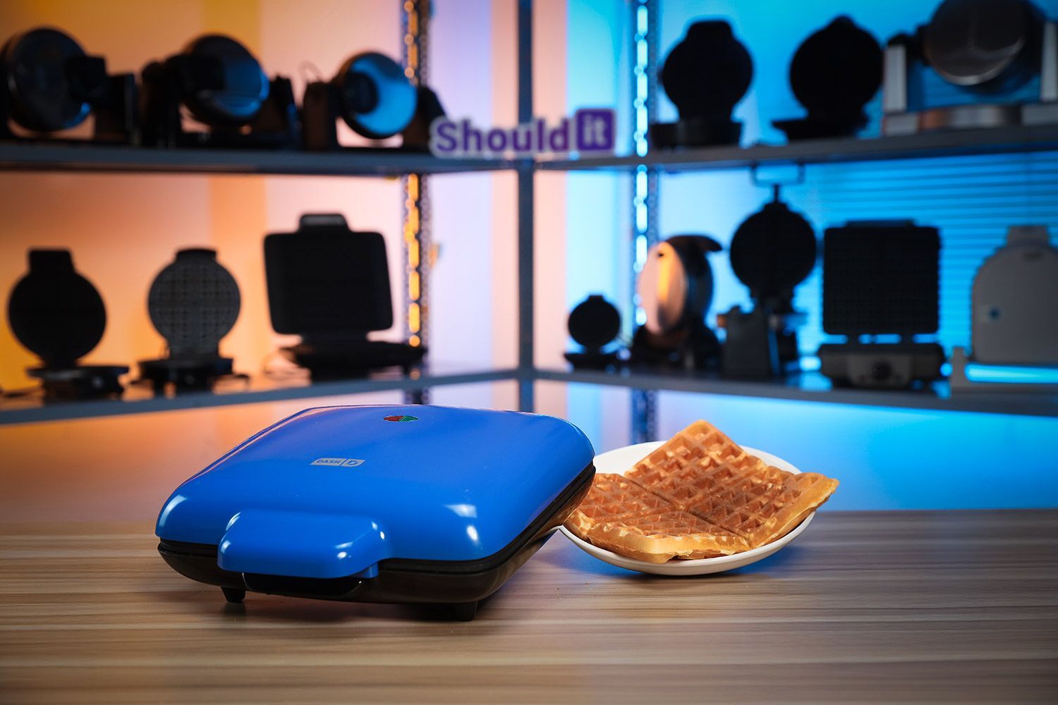 DASH No-Drip Waffle Maker next to a pile of fresh golden waffles.