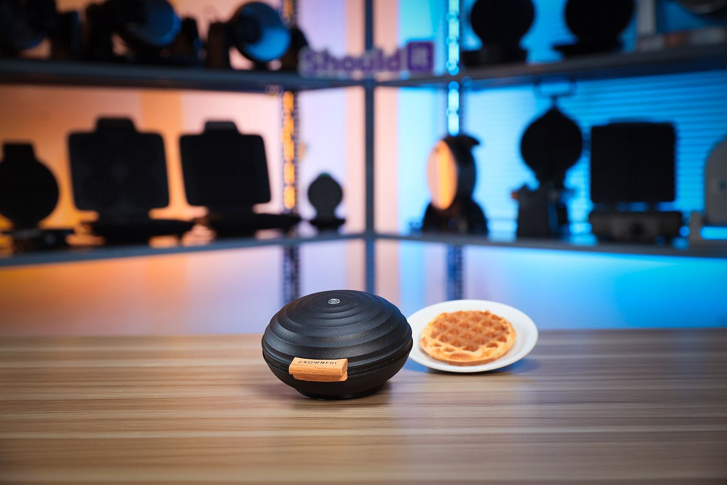 Crownful Mini waffle maker with its lid opened and a fresh waffle inside. Next to it is a stack of mini waffles.