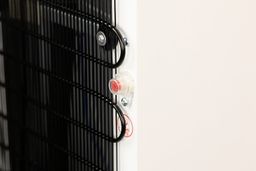 Close up of a red colored drainage plug with a protective screw cap at the rear of a water cooler dispenser.