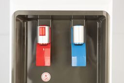 A close up of two dispensing levers on a water cooler dispenser. The left red lever dispenses hot water and the blue cold.