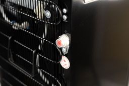 The water drainage plug with a protective plastic screw cap at the back of a water cooler dispenser.