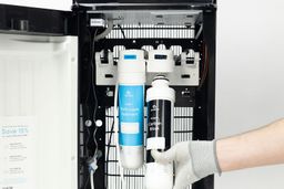 A demonstration on how to insert a water filter into the bracket of a water cooler dispenser.