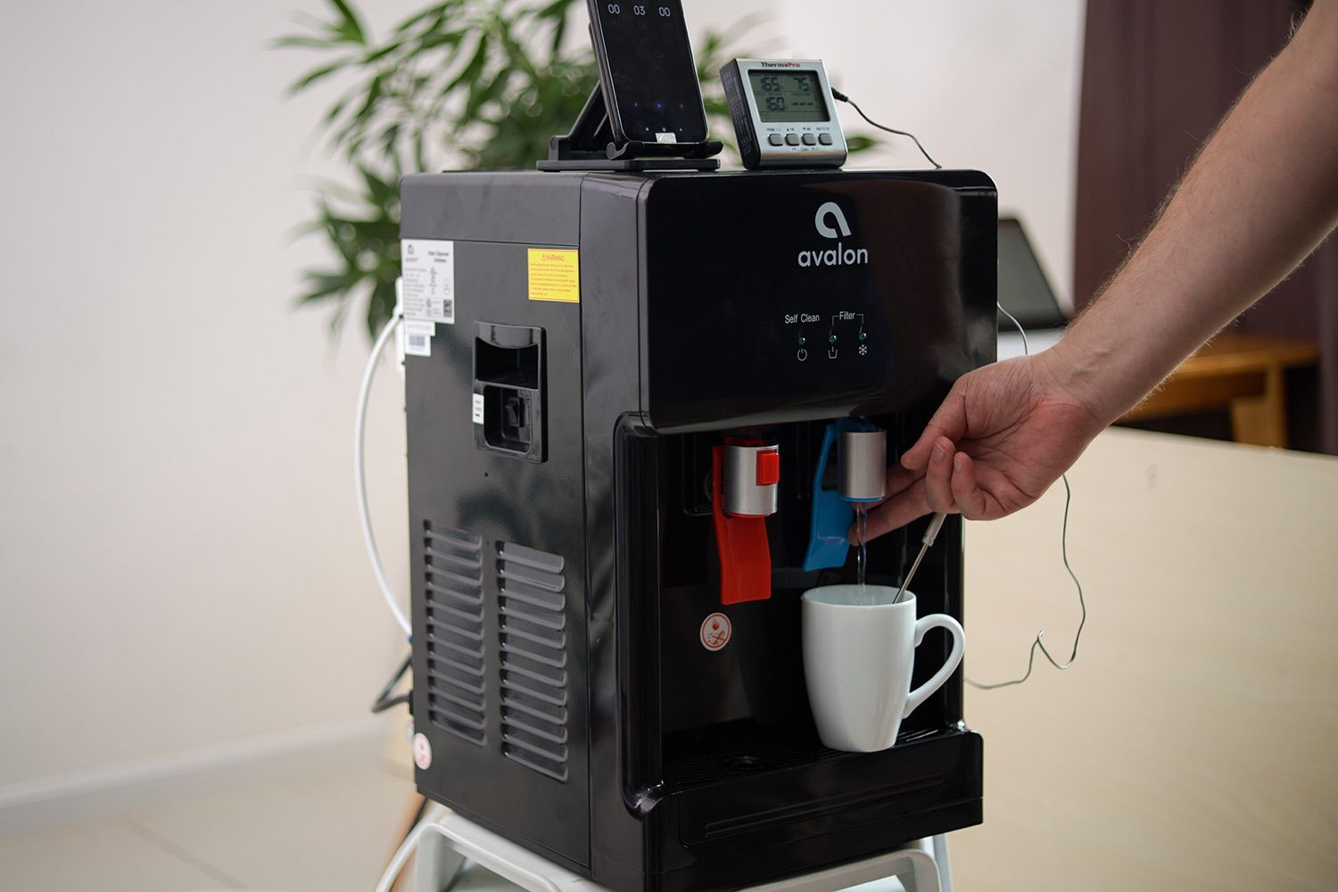 Water temperature being measured as cold water flows out the nozzle of a water cooler dispenser.