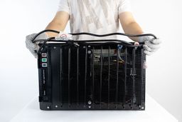 A man holding the cord of a small countertop water cooler dispenser wrapped twice along its horizontal length.