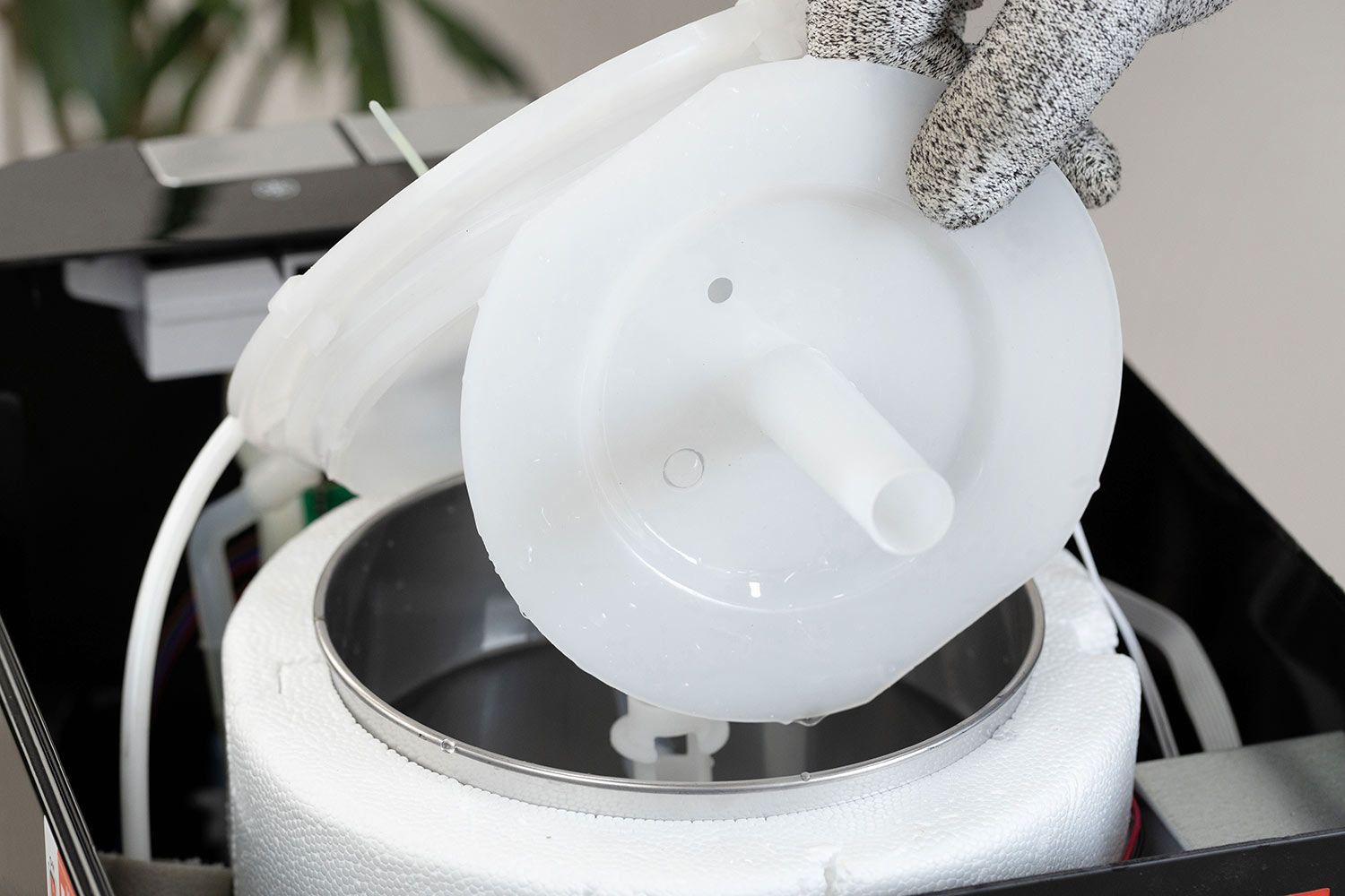 A water baffle removed from inside the cold water tank of a water cooler dispenser and displayed above the tank.