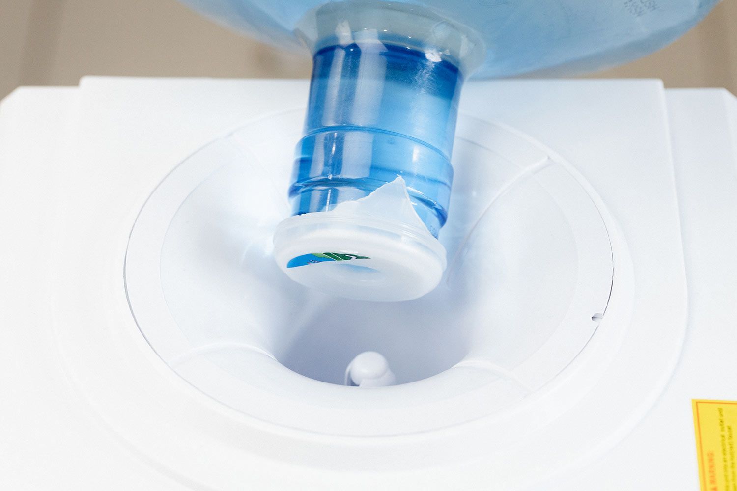 A bottle being loaded onto a top-loading water cooler dispenser.