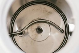 The empty cold water tank of a water cooler dispenser needing to be cleaned.