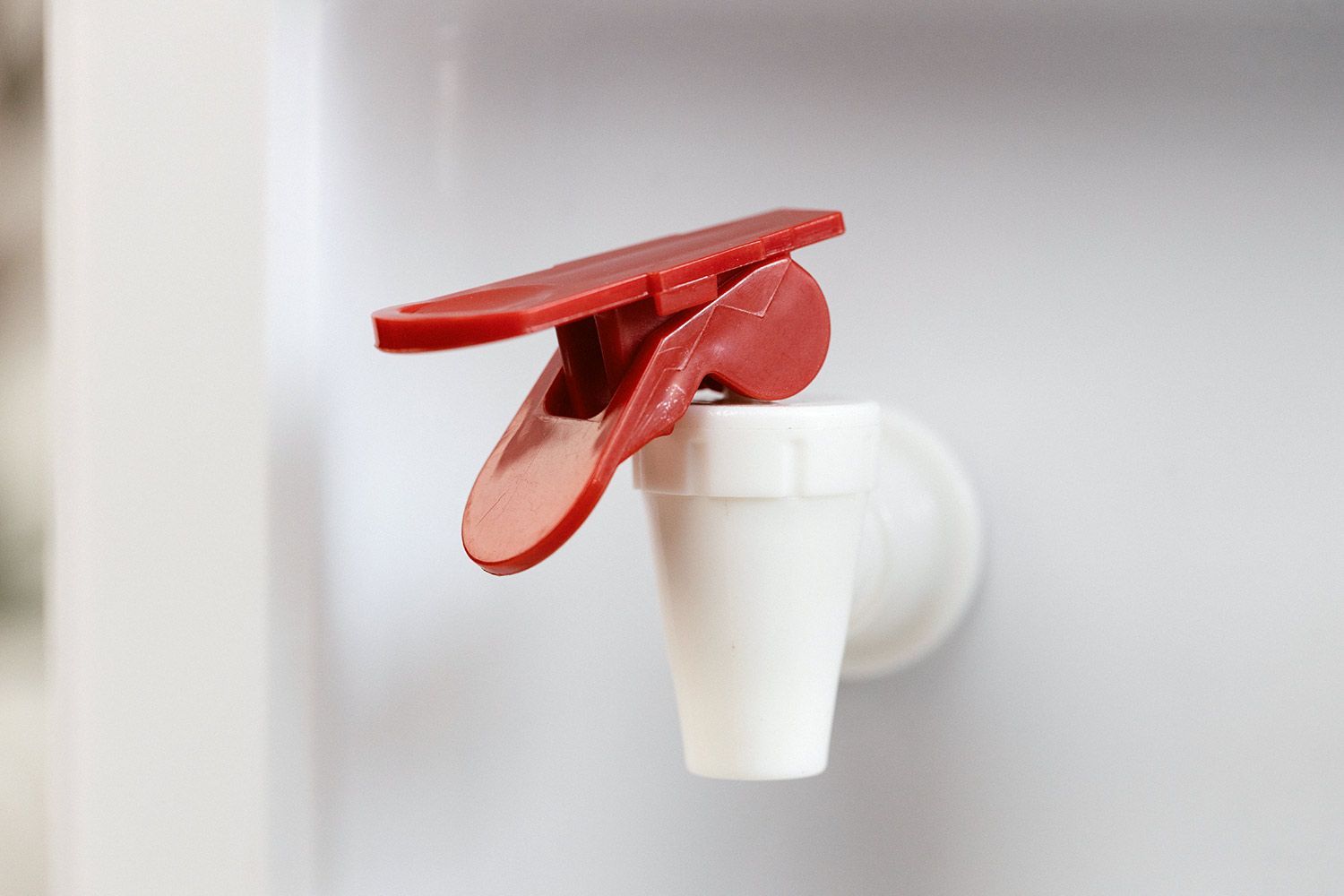 A close up of a hot water faucet with a safety clip on a water cooler dispenser.