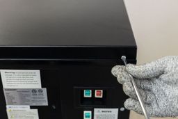 The middle button of a water cooler dispenser being held down to assess the ease of cleaning between the buttons.