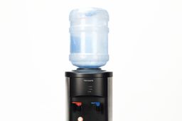 A water bottle set in place on a top loading water cooler dispenser.