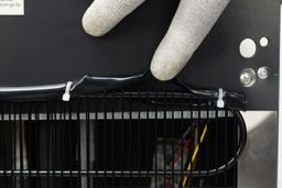 A plastic cover over top top of a rear metal grate of a water cooler dispenser.