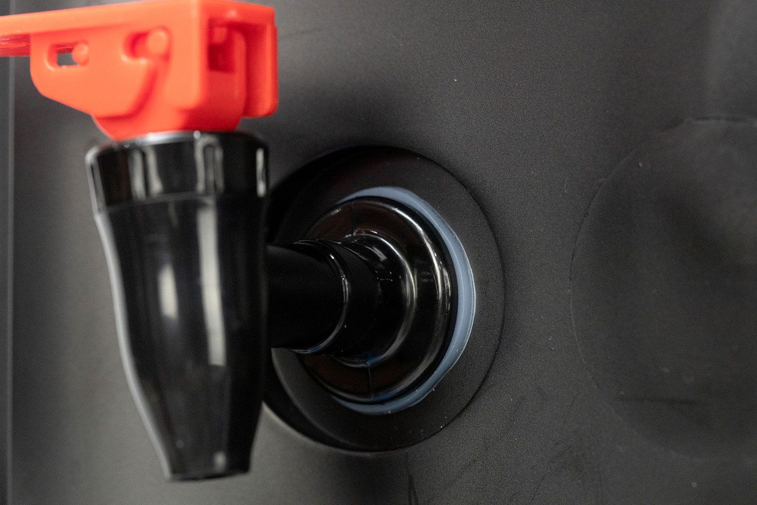 Close up of a hot water dispensing lever and safety mechanism on a water cooler dispenser.