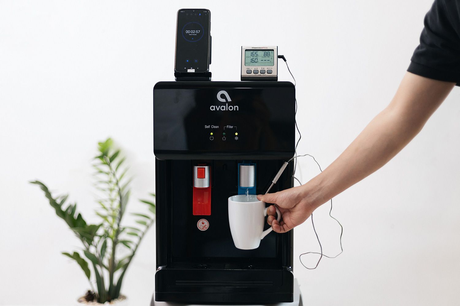 A water test setup measuring the cold water temperature of a small countertop water cooler dispenser.