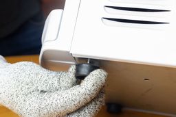 A gloved hand showing how to adjust a rubber stump leg on a water cooler dispenser.