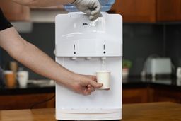 A person dispensing cold water from the Igloo bottled water cooler dispenser.