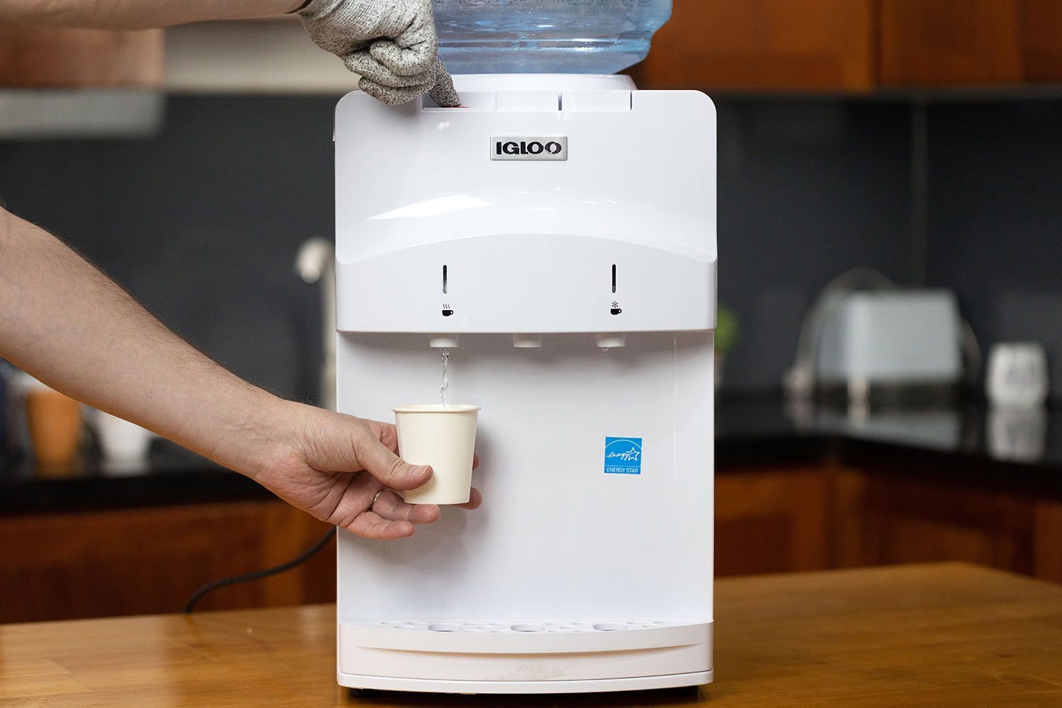 A person dispensing hot water from the Igloo hot and cold water cooler dispenser.