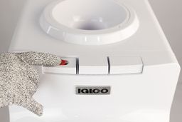 A gloved finger showing how to operate a hot water safety mechanism on the button of a hot water cooler dispenser.