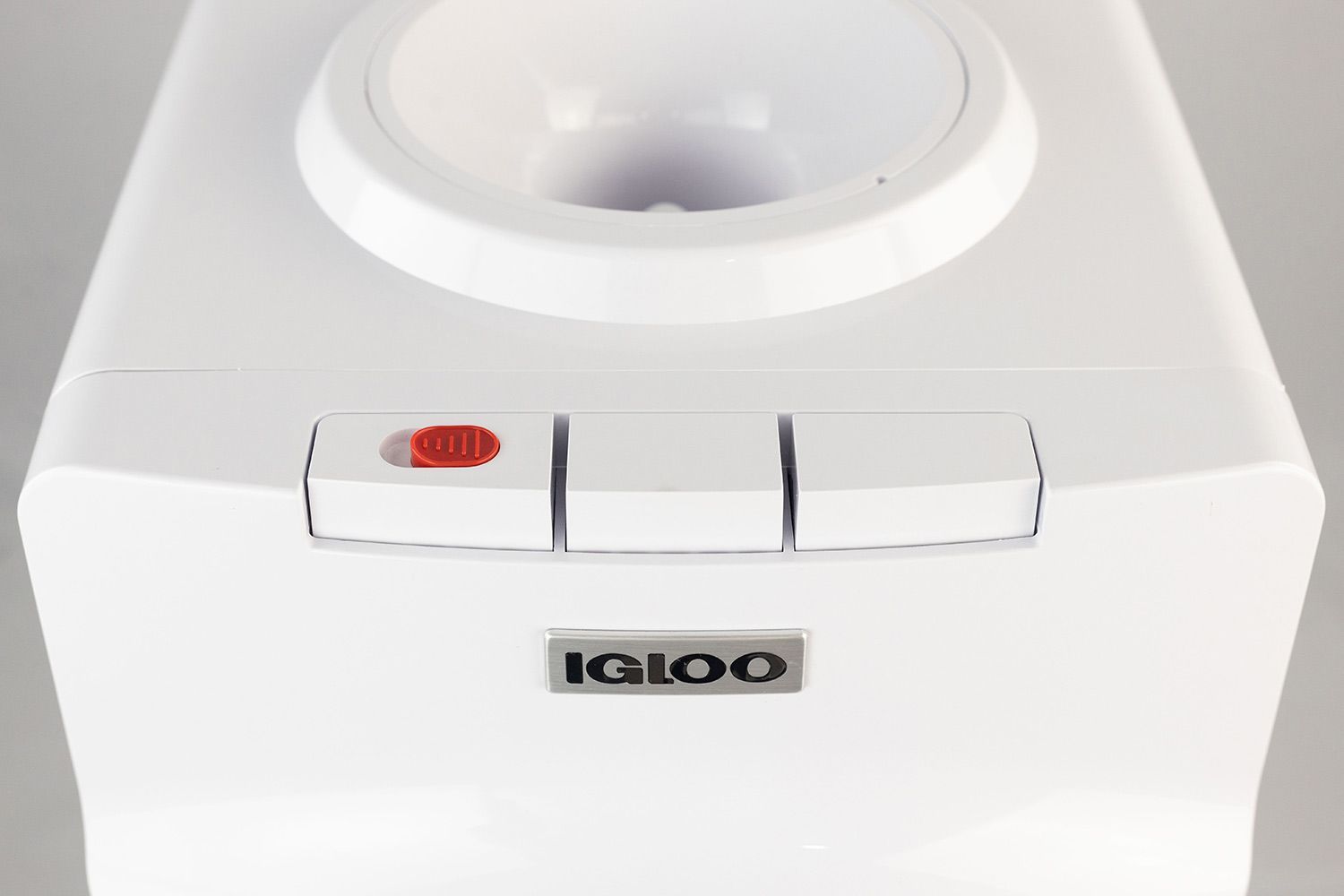 A close up top down view of three white buttons of a water cooler dispenser.