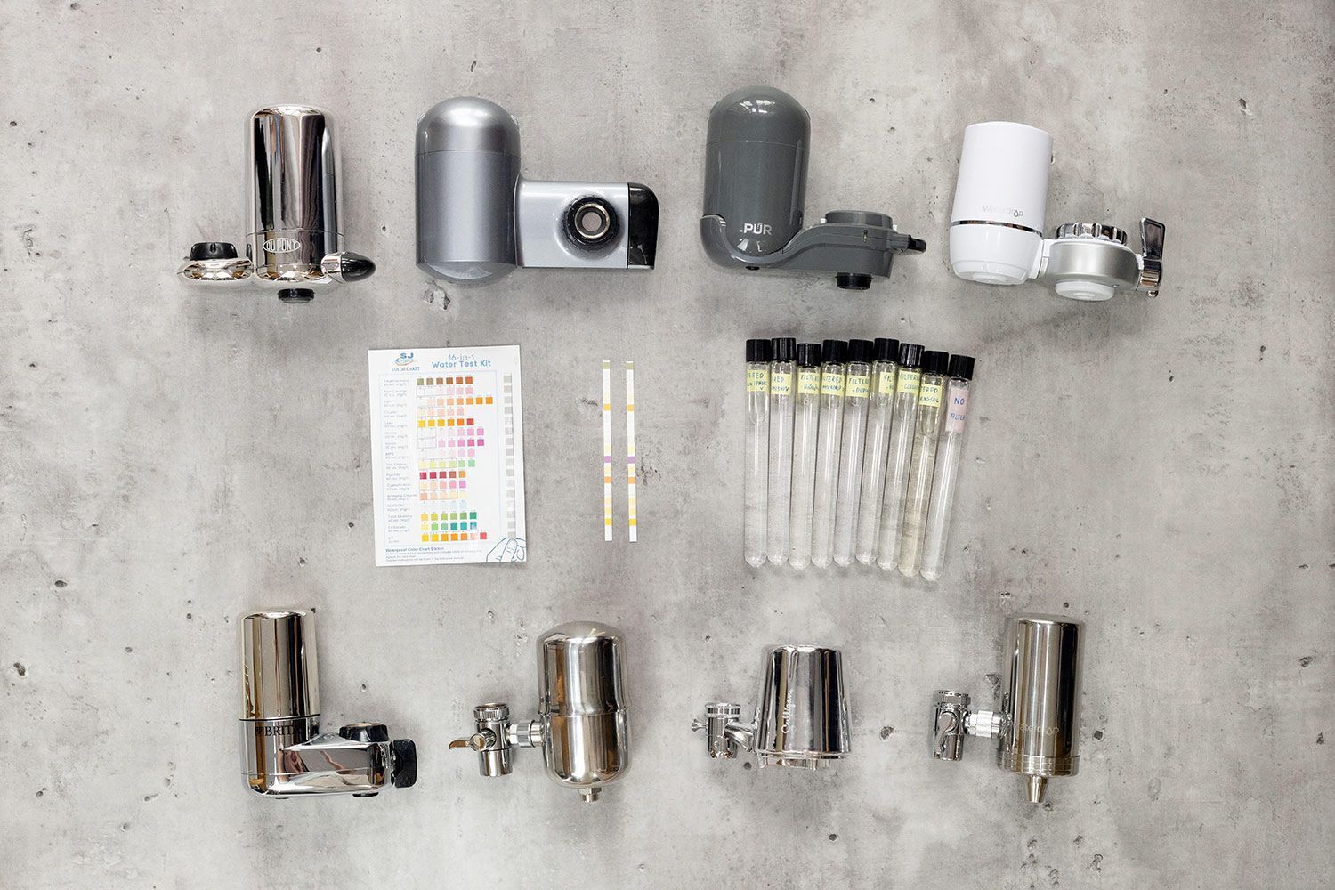 Eight faucet-mount water filters arranged in two rows, with the water testing kit and sampling vials in the middle.