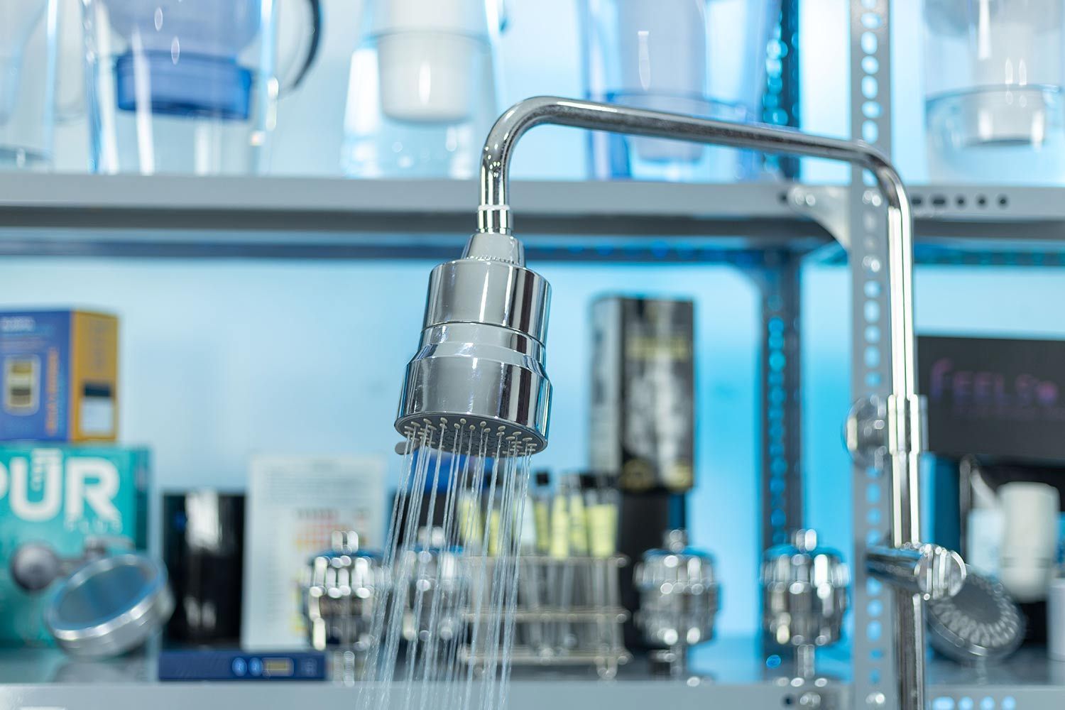 The MZXBold shower filter as installed and in use, a shelf full of shower filters and pitchers in the background